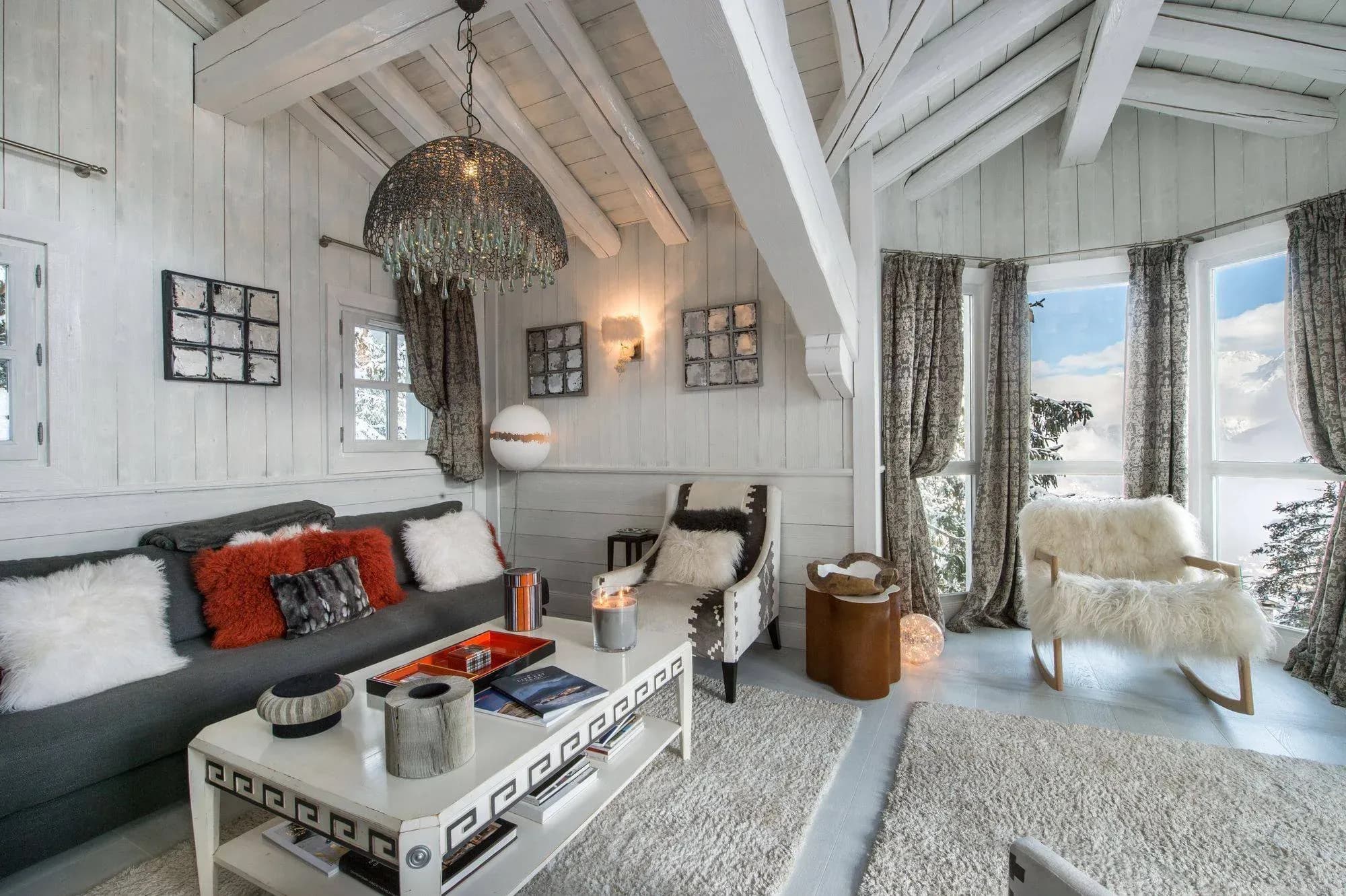 Lounge with grey sofa, armchairs, sheepskin rocking chair and corner windows with mountain views