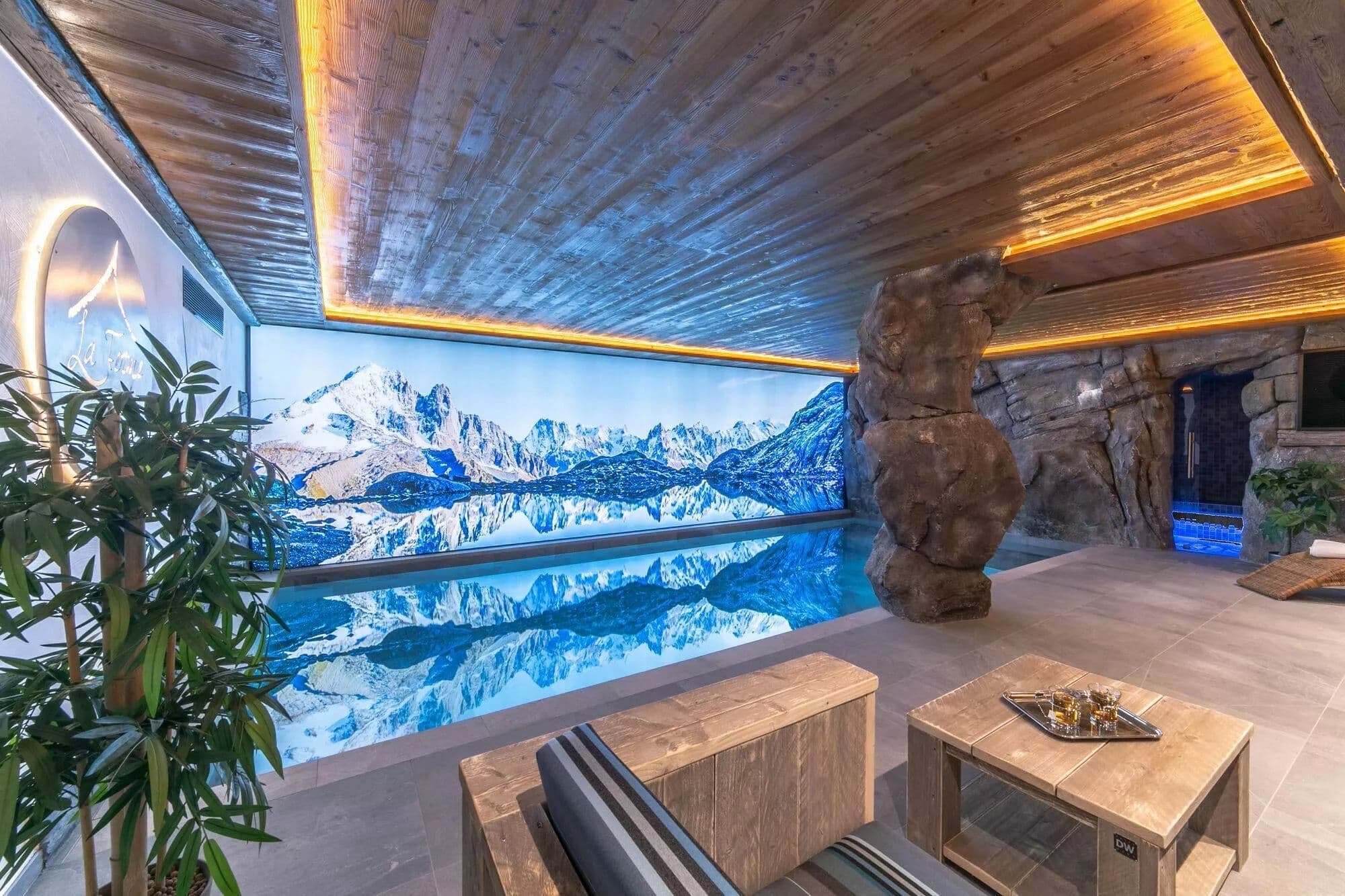 Indoor swimming pool with fireside seating and an Alpine wall mural