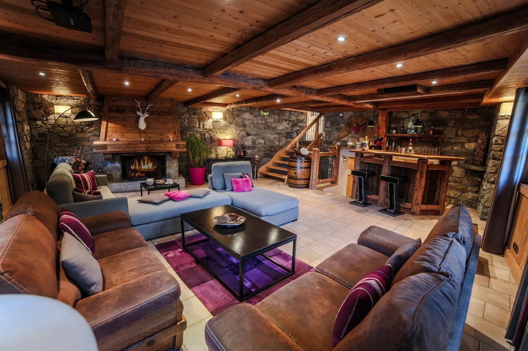 Timber-lined lounge with sofas, a fireplace and the dining area beyond