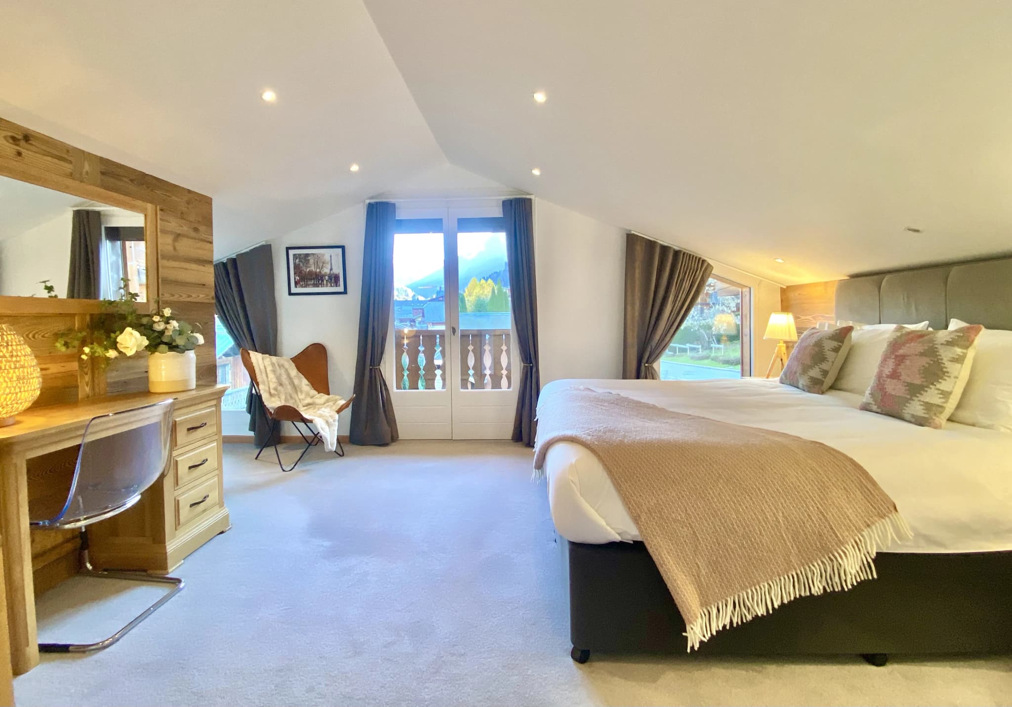 Double bedroom beneath a vaulted timber ceiling with balcony access
