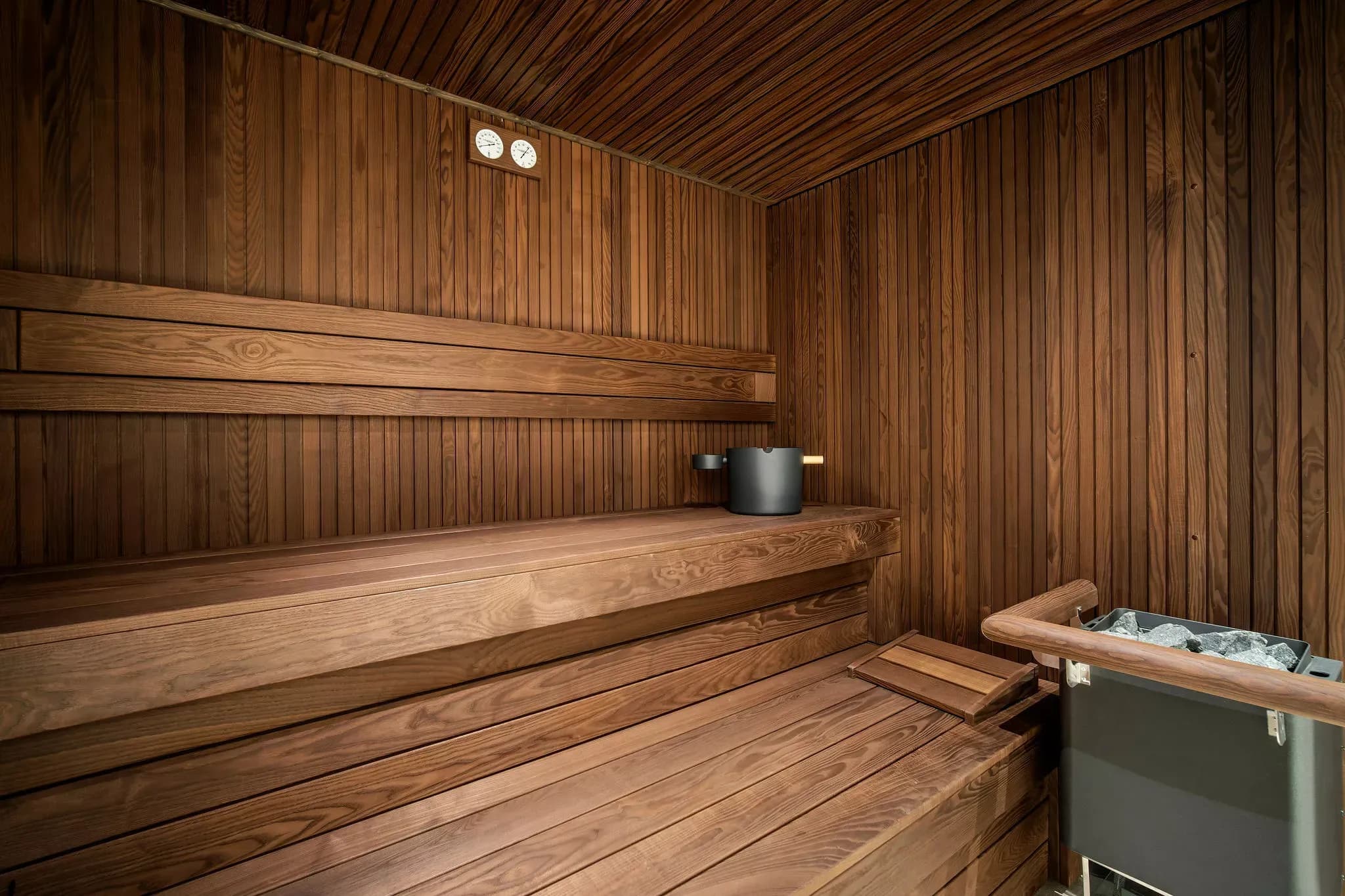 Private wood-panelled sauna with bench seating and a sauna stove