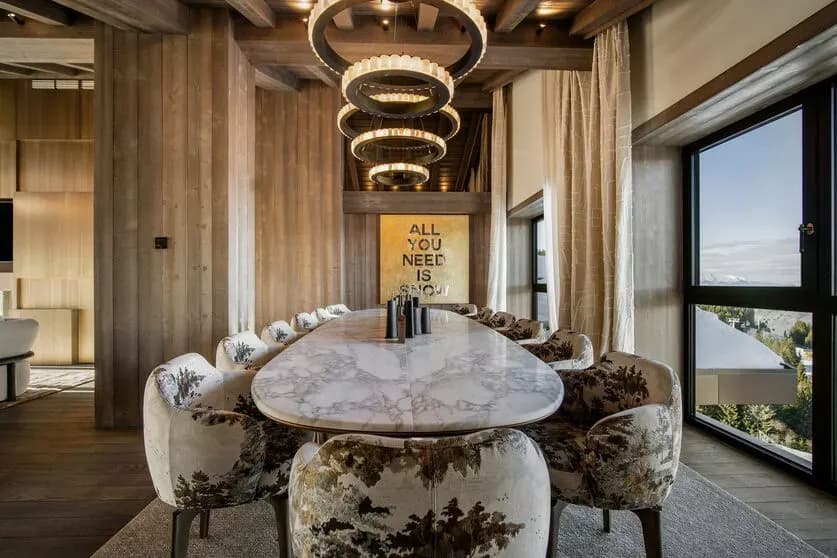 Dining table beneath pendant lights beside mountain-facing windows