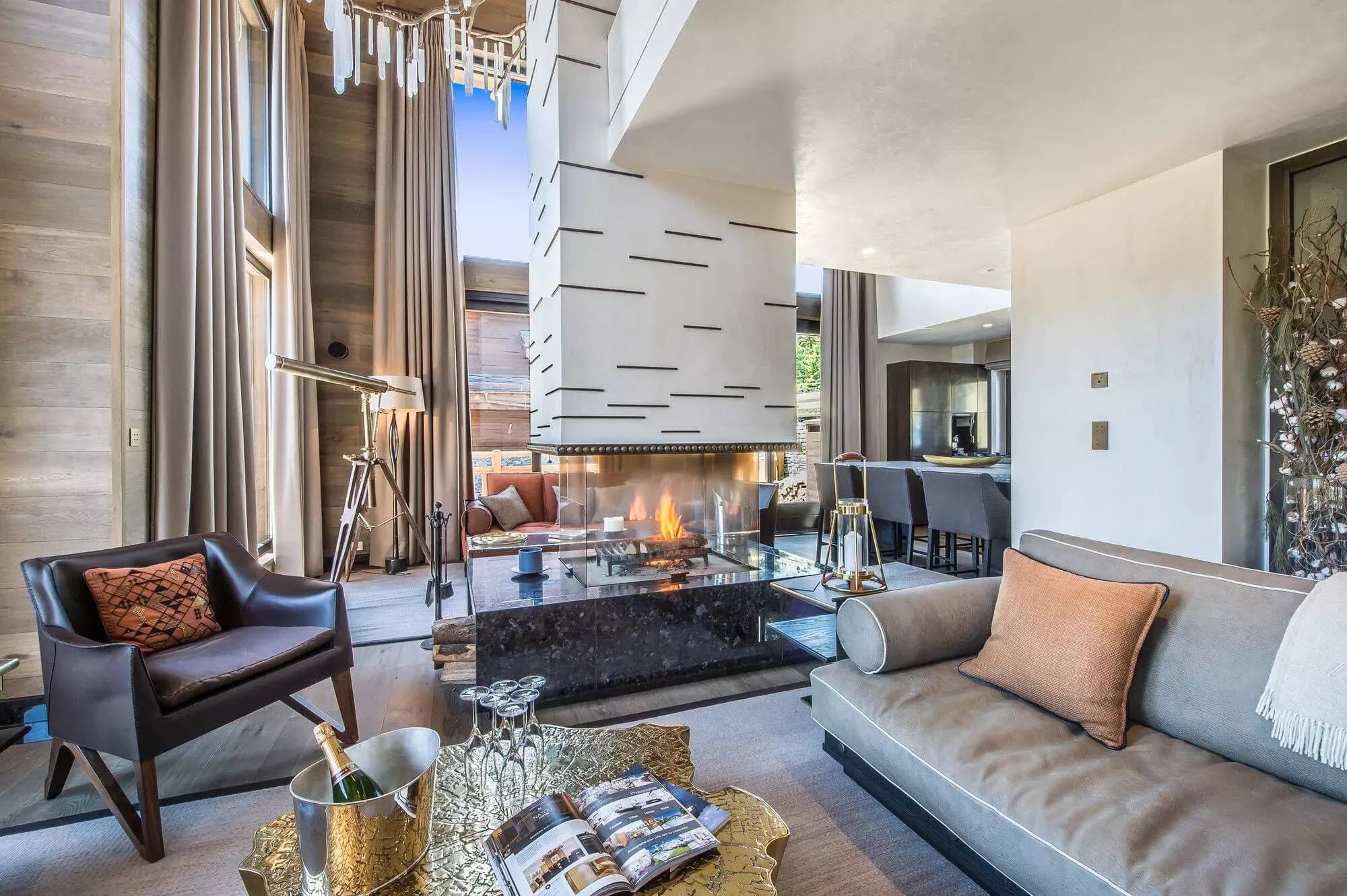 Open-plan living room with central wood fireplace, lounge seating and dining area