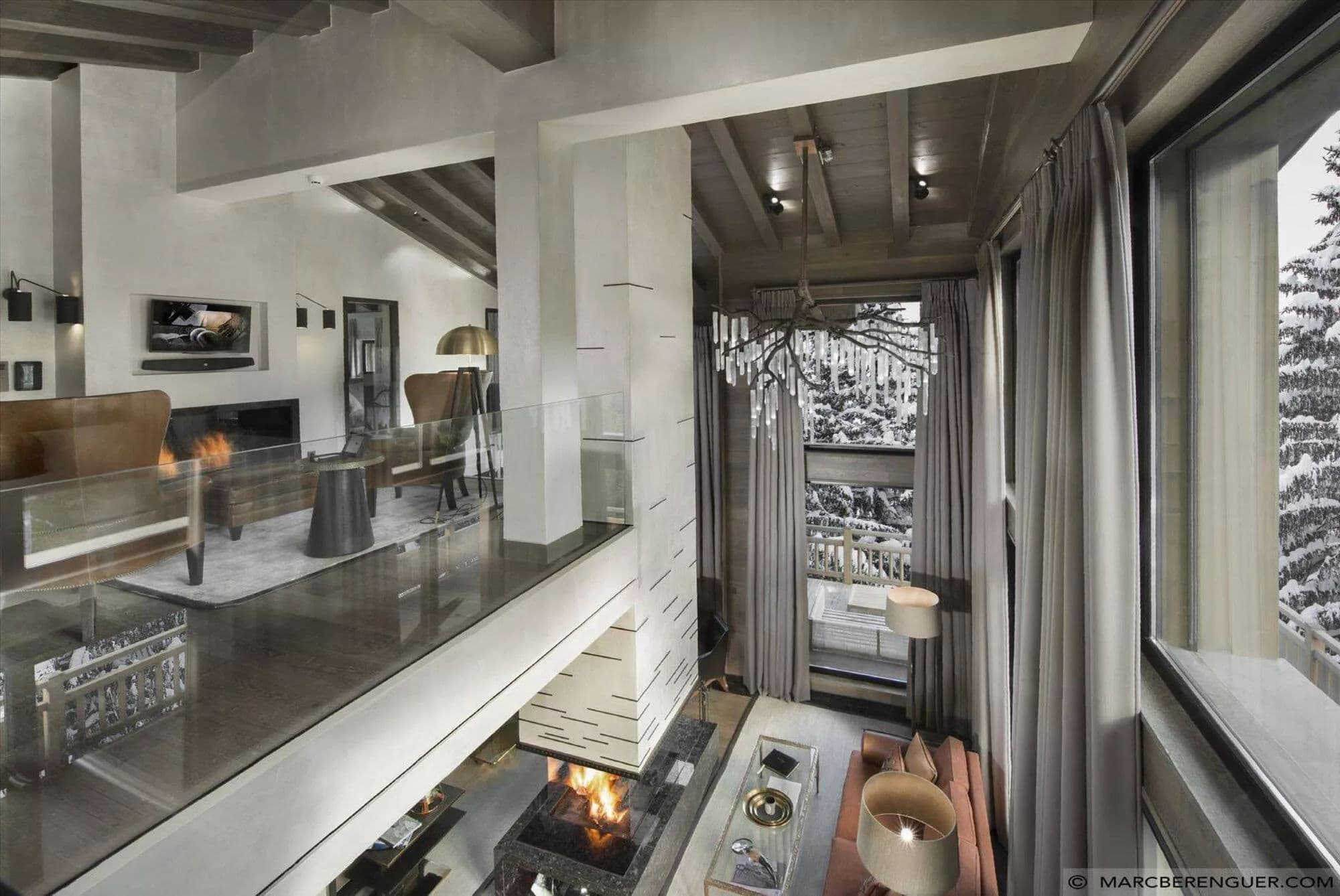 Double-height living room with fireside seating, mezzanine lounge and snowy views
