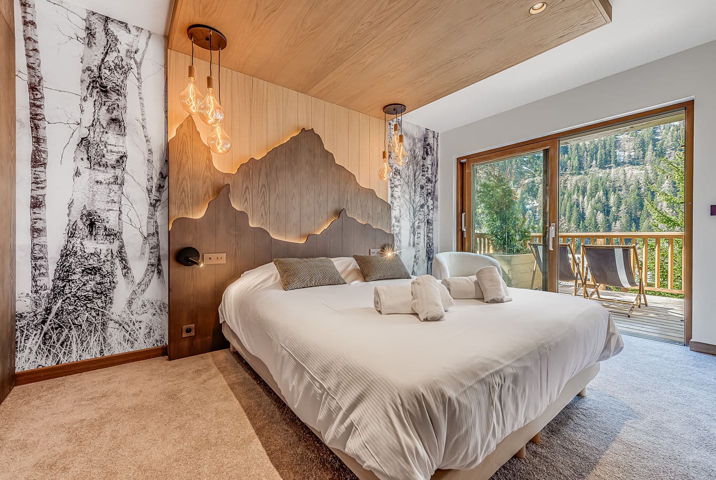 Primary bedroom with king bed and forest views; heated wood ceiling detail