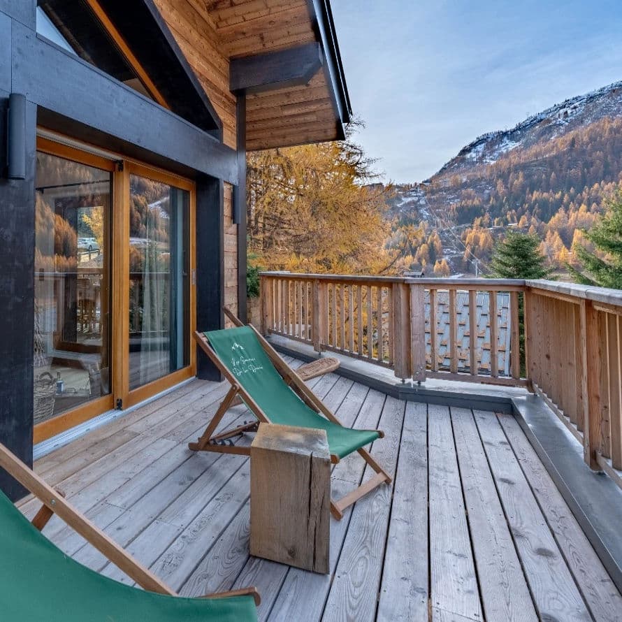 Expansive deck with valley views; larch forest backdrop and snow-capped peaks visible