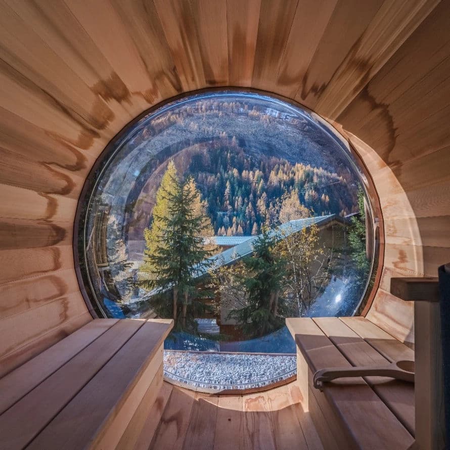 Sauna interior with circular window framing forested valley and bridge