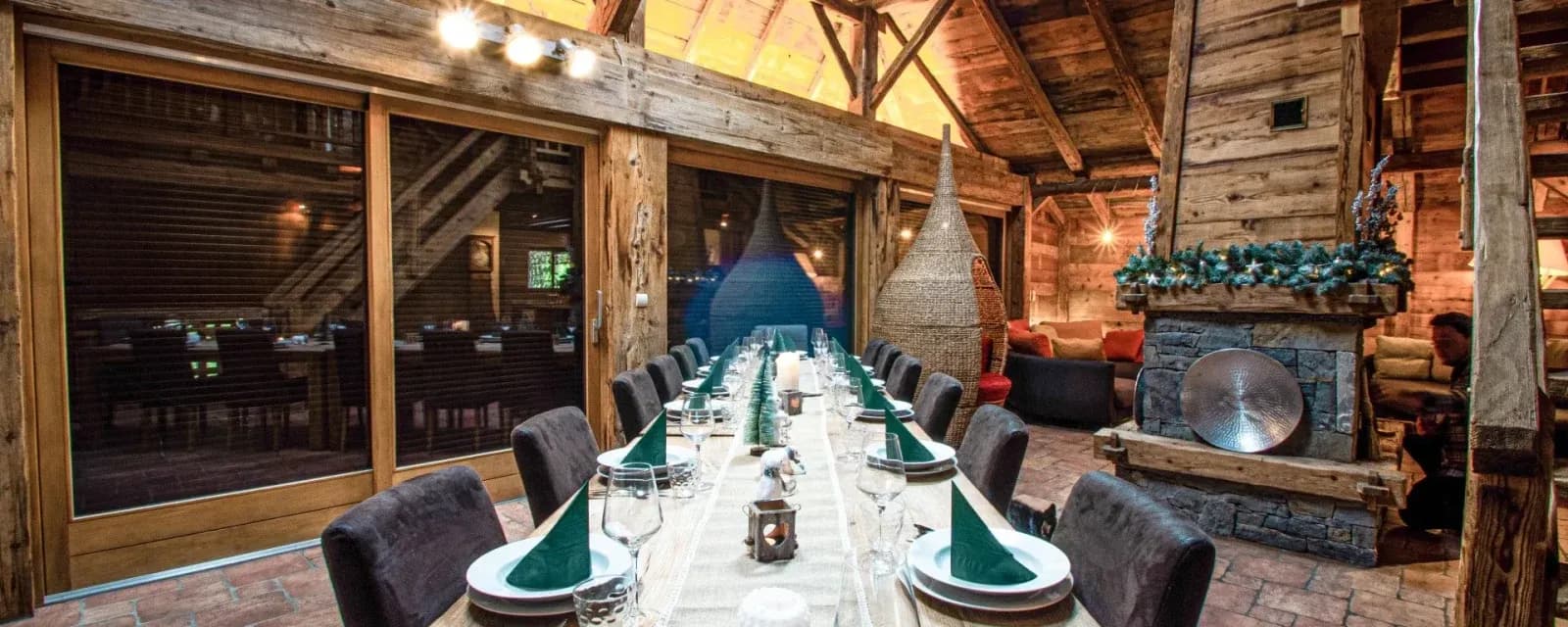 Long dining table set beside the open fireplace and balcony doors