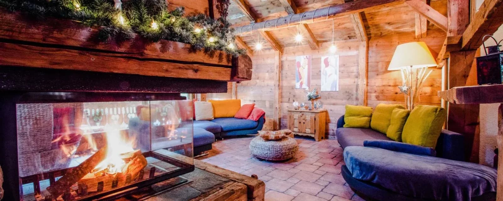Open fireplace with colourful sofas beneath timber rafters