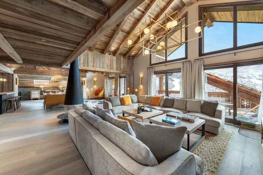 Double-height living and dining room with a suspended fireplace and mountain-facing windows