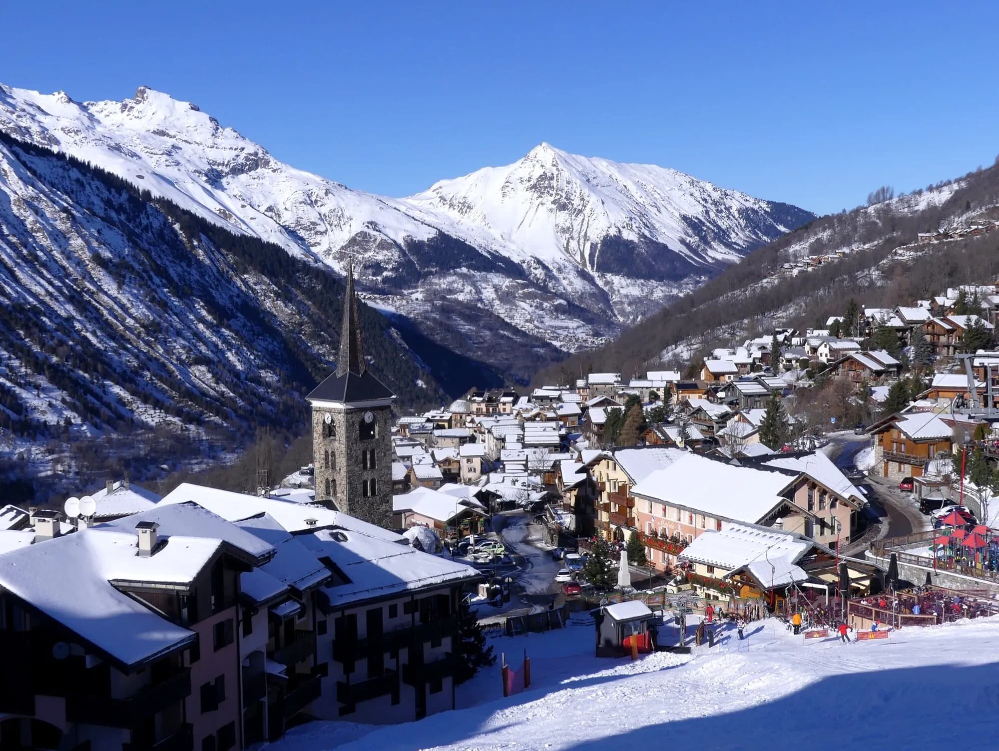 The church spire and snowy rooftops of Saint-Martin-de-Belleville below white peaks.