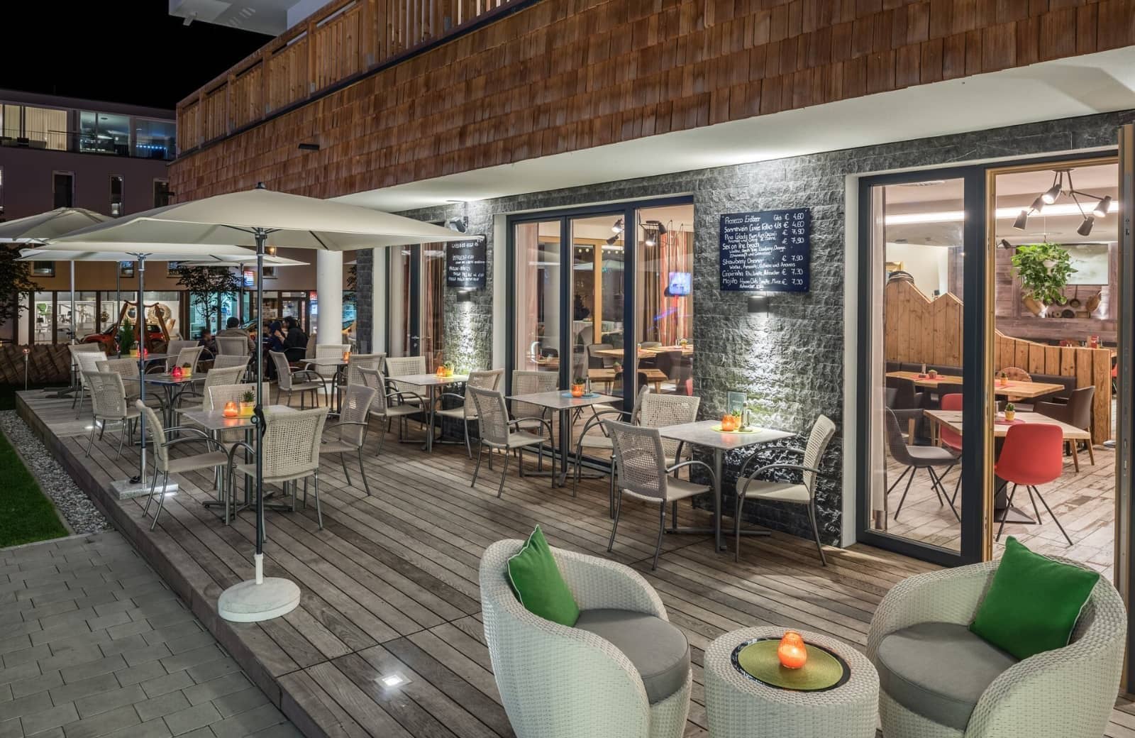 Deck patio with dining tables and lounge seating; illuminated for evening use