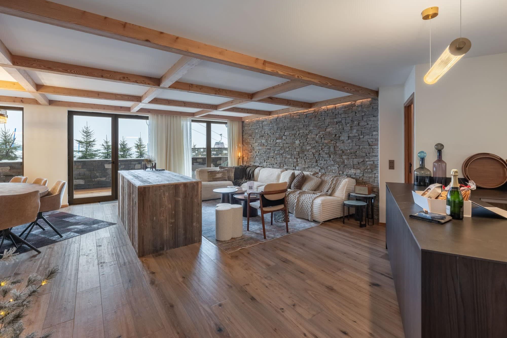 Open-plan living area with timber ceiling, stone feature wall and balcony access