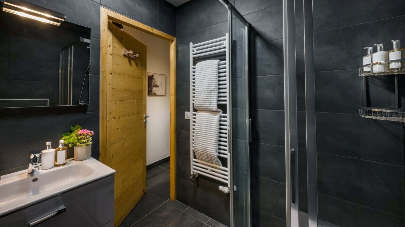 Dark-tiled shower room with a basin and heated towel rail
