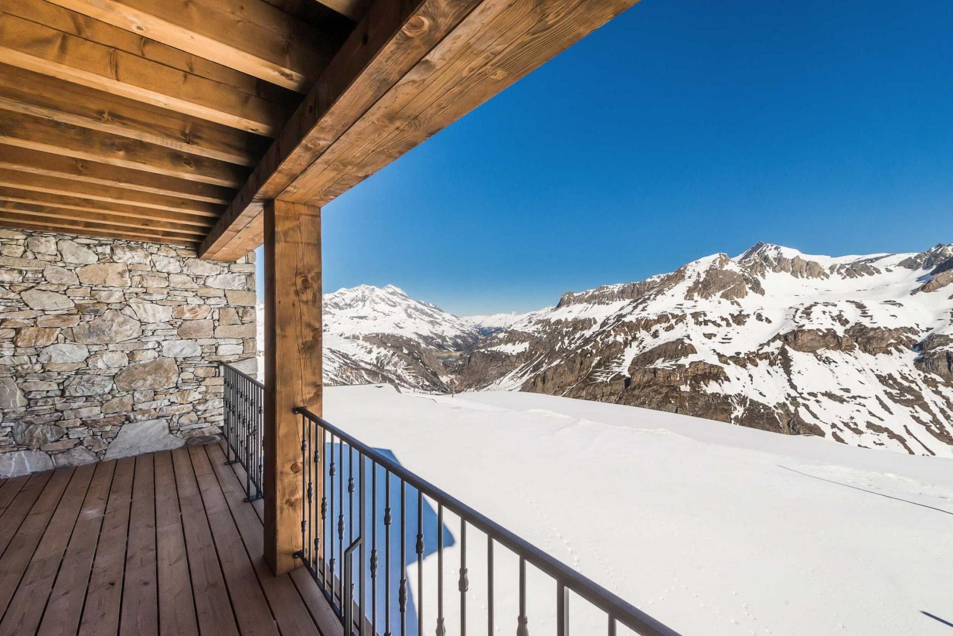 Covered timber balcony with stone masonry and panoramic Alpine views