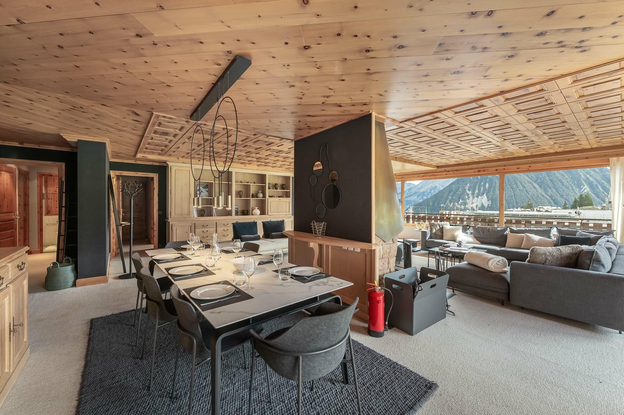 Open-plan living and dining area with central wood fireplace and panoramic windows