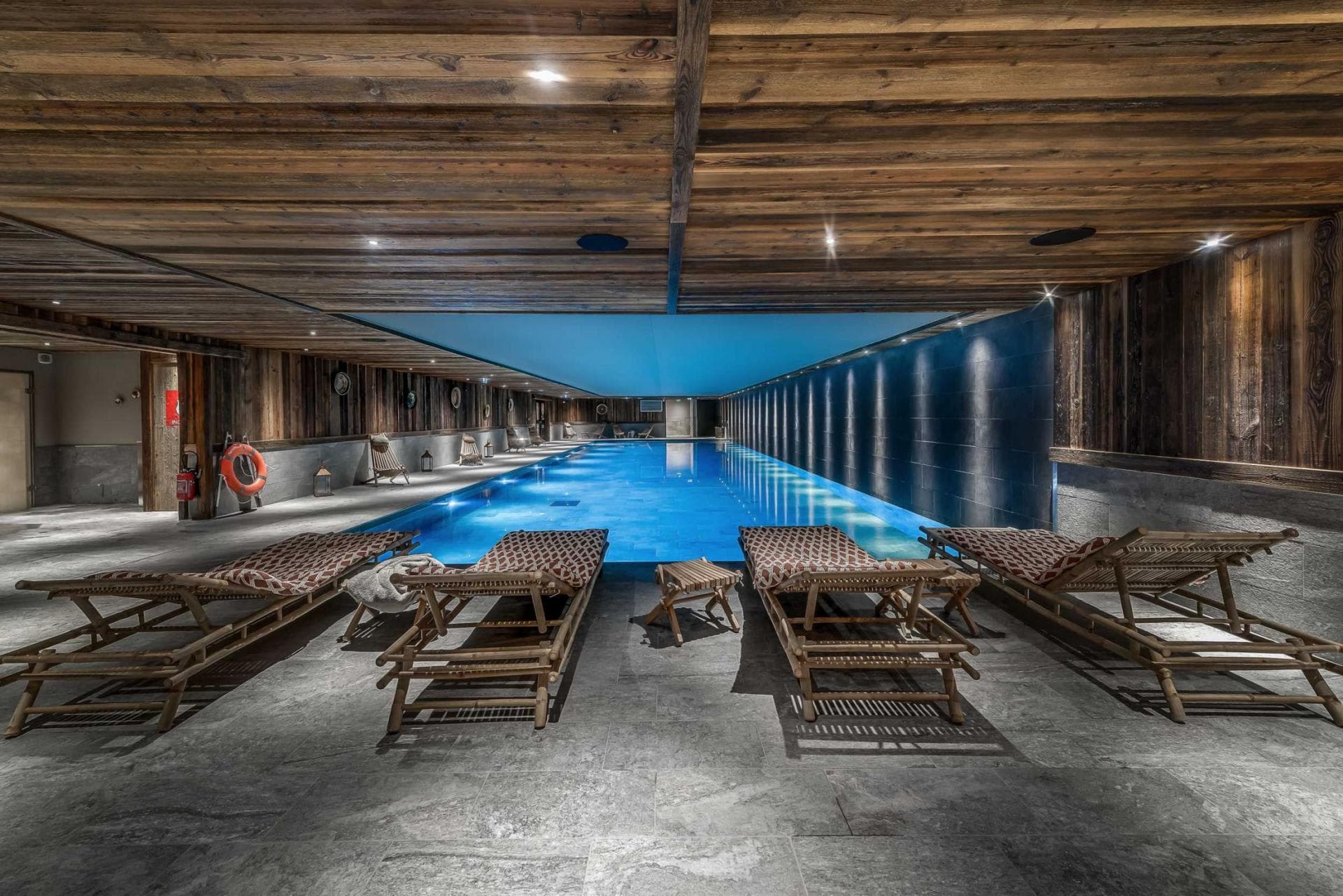 Indoor heated lap pool with reclaimed wood ceiling and loungers