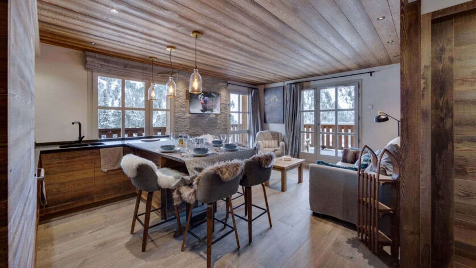 Open-plan kitchen and living area with balcony access and snowy mountain views