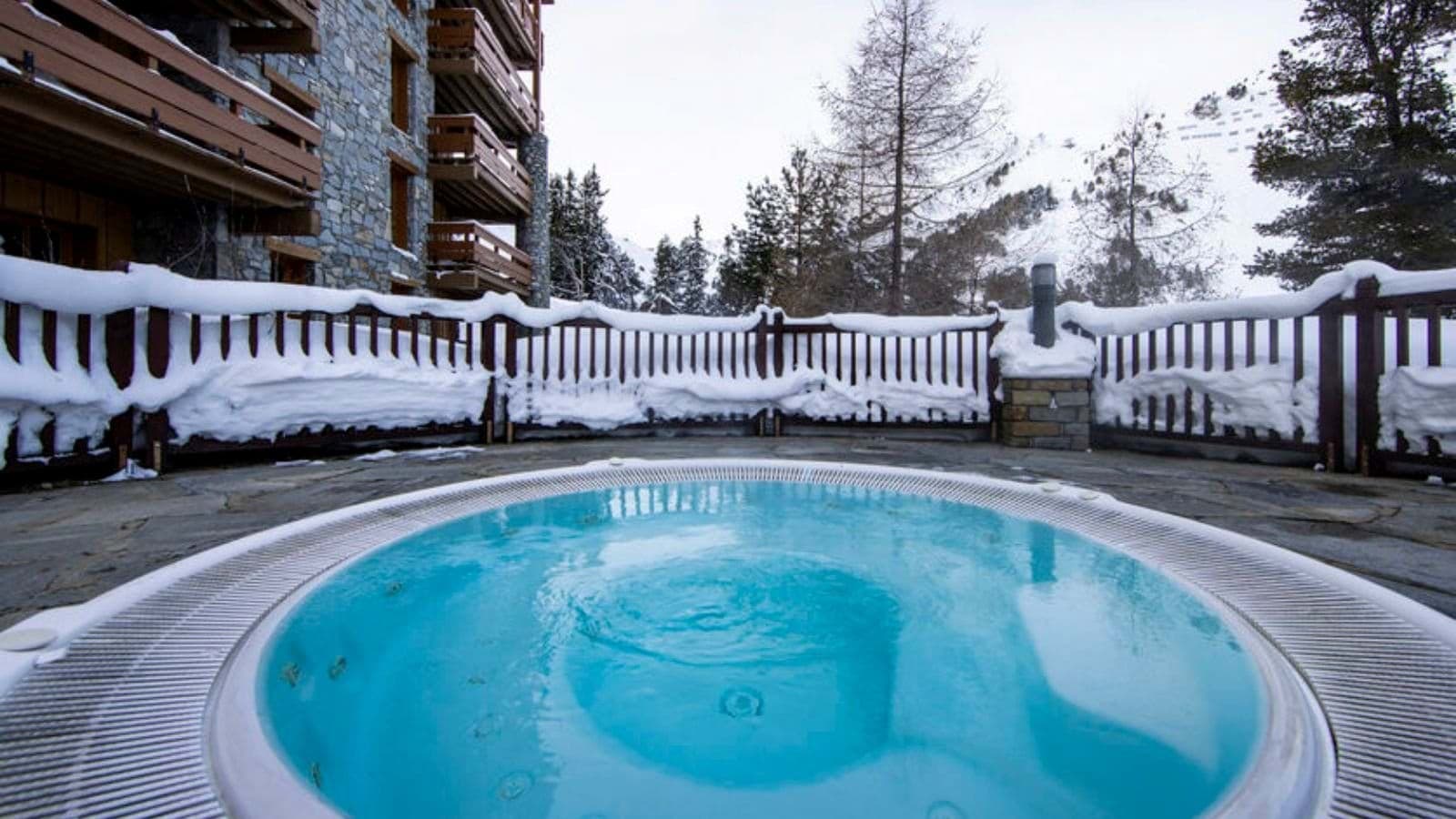 Shared outdoor hot tub with stone terrace and mountain views