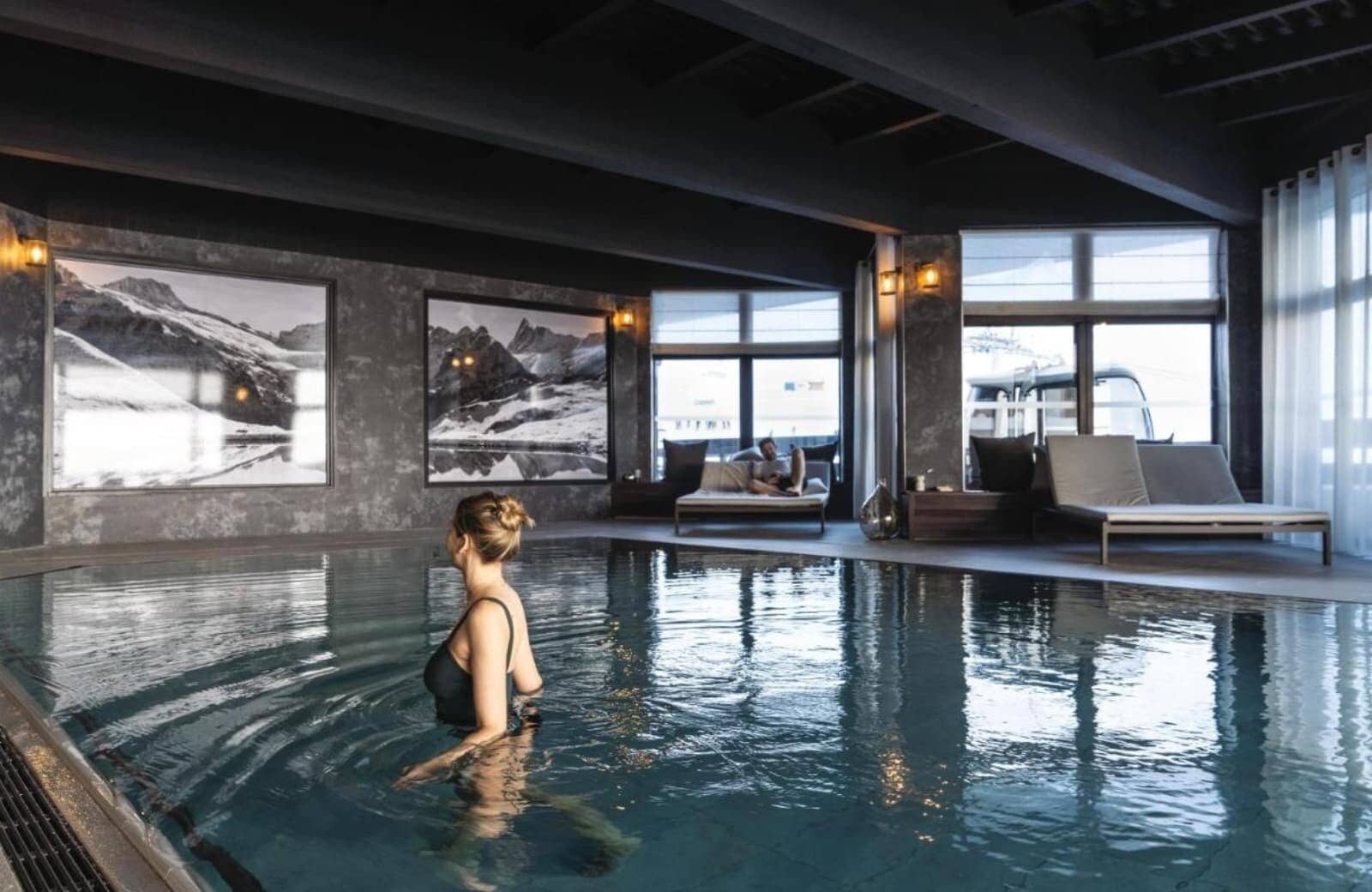 Indoor heated pool with poolside loungers and mountain-themed artwork