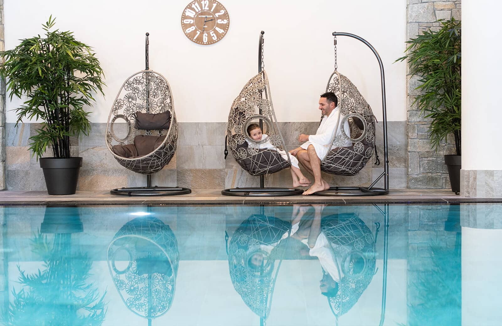 Indoor pool with three hanging wicker swing chairs