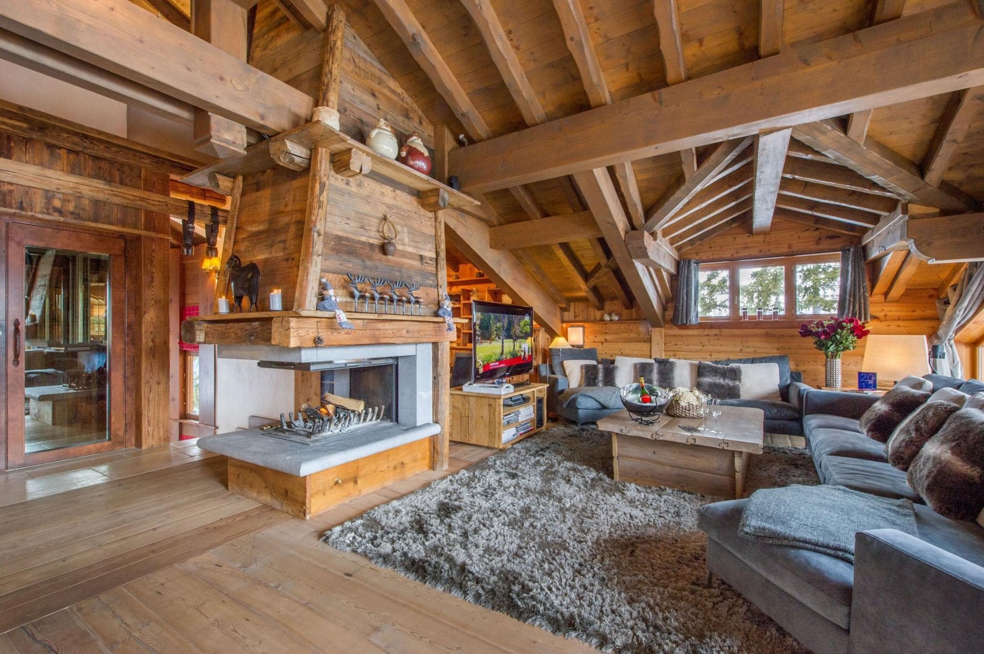 Open-plan living room arranged around the central wood fireplace