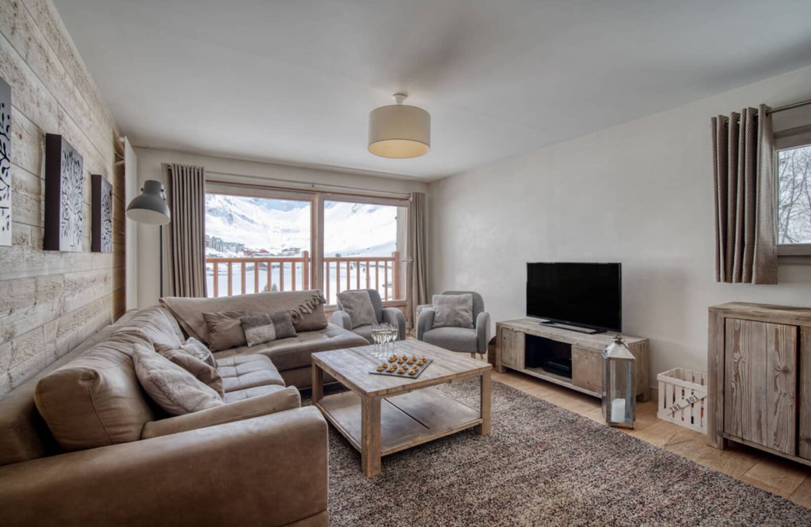 Living room with sectional seating, wood-burning fireplace, and mountain balcony views