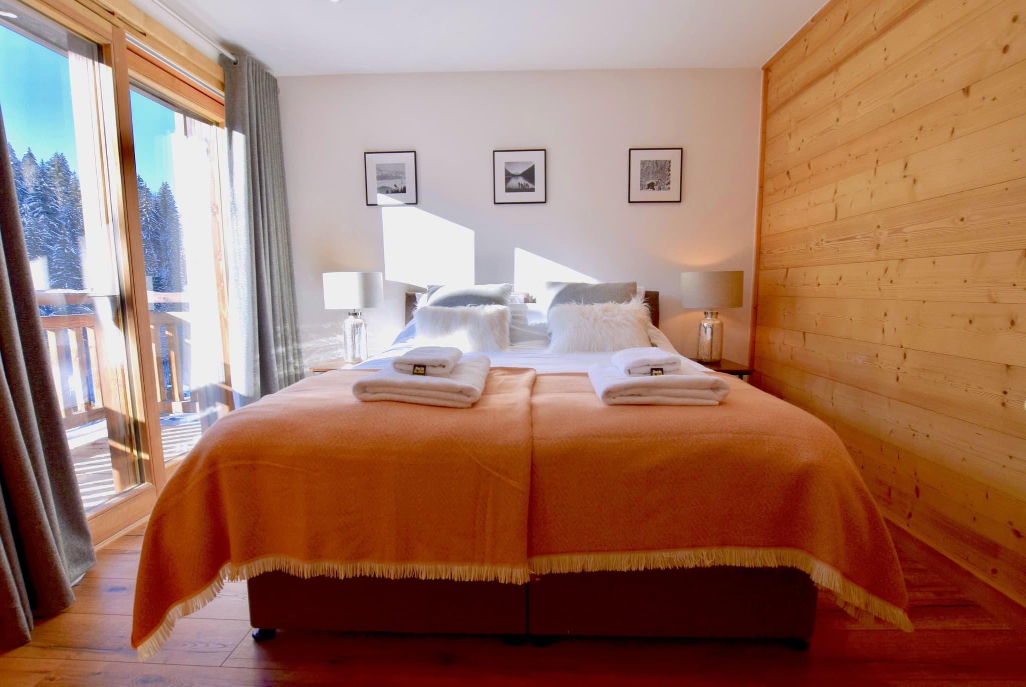 Primary bedroom with twin beds, wood paneling, and balcony with mountain views