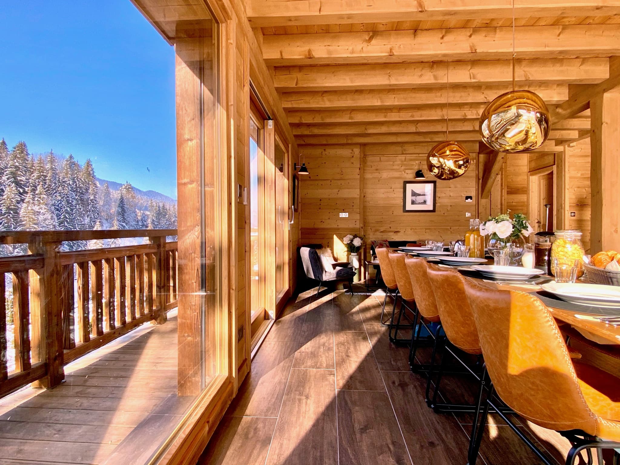 Dining area seats 8; floor-to-ceiling windows frame snowy mountain valley views