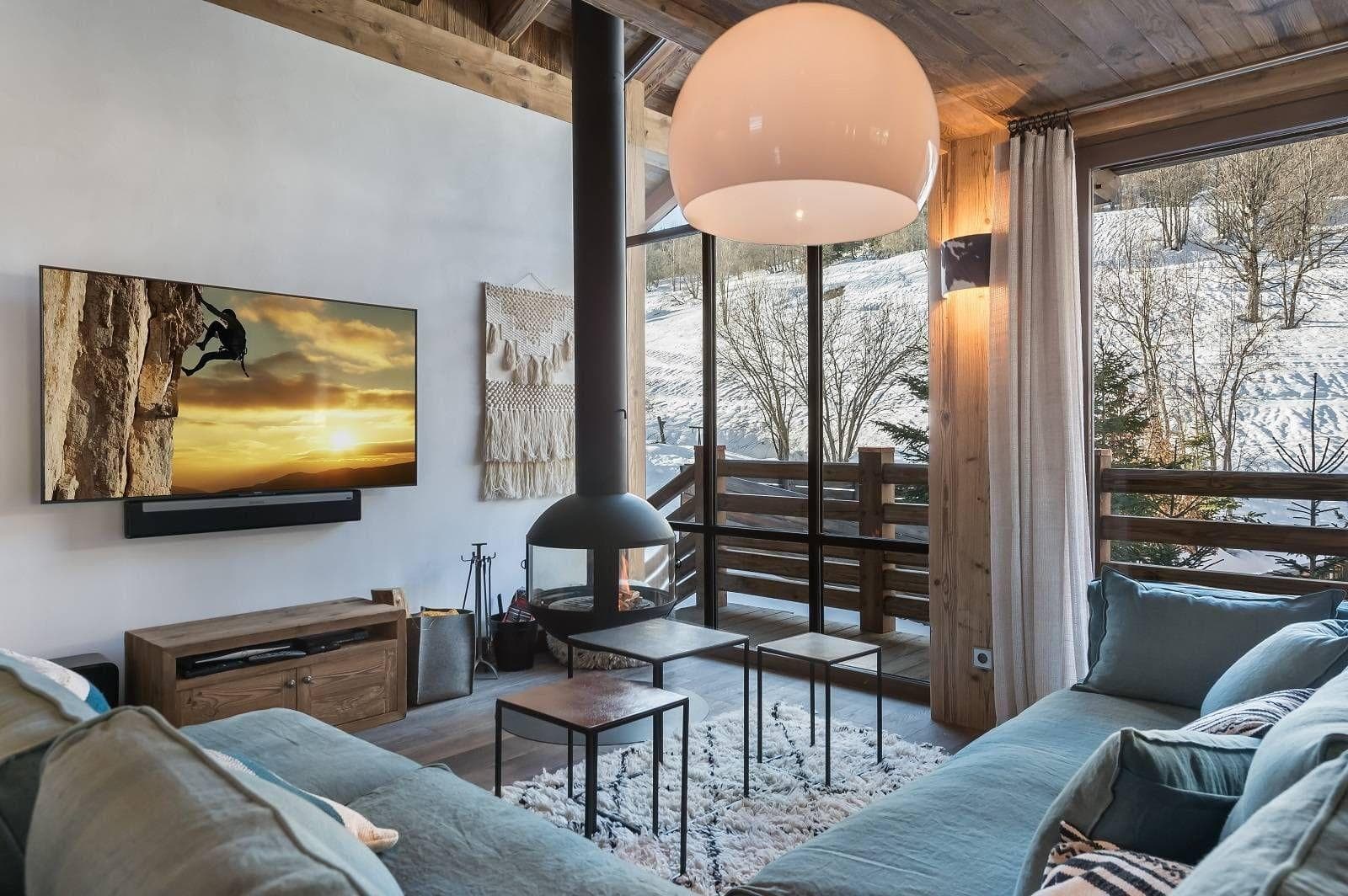Open-plan lounge with a wood fireplace, television and balcony doors