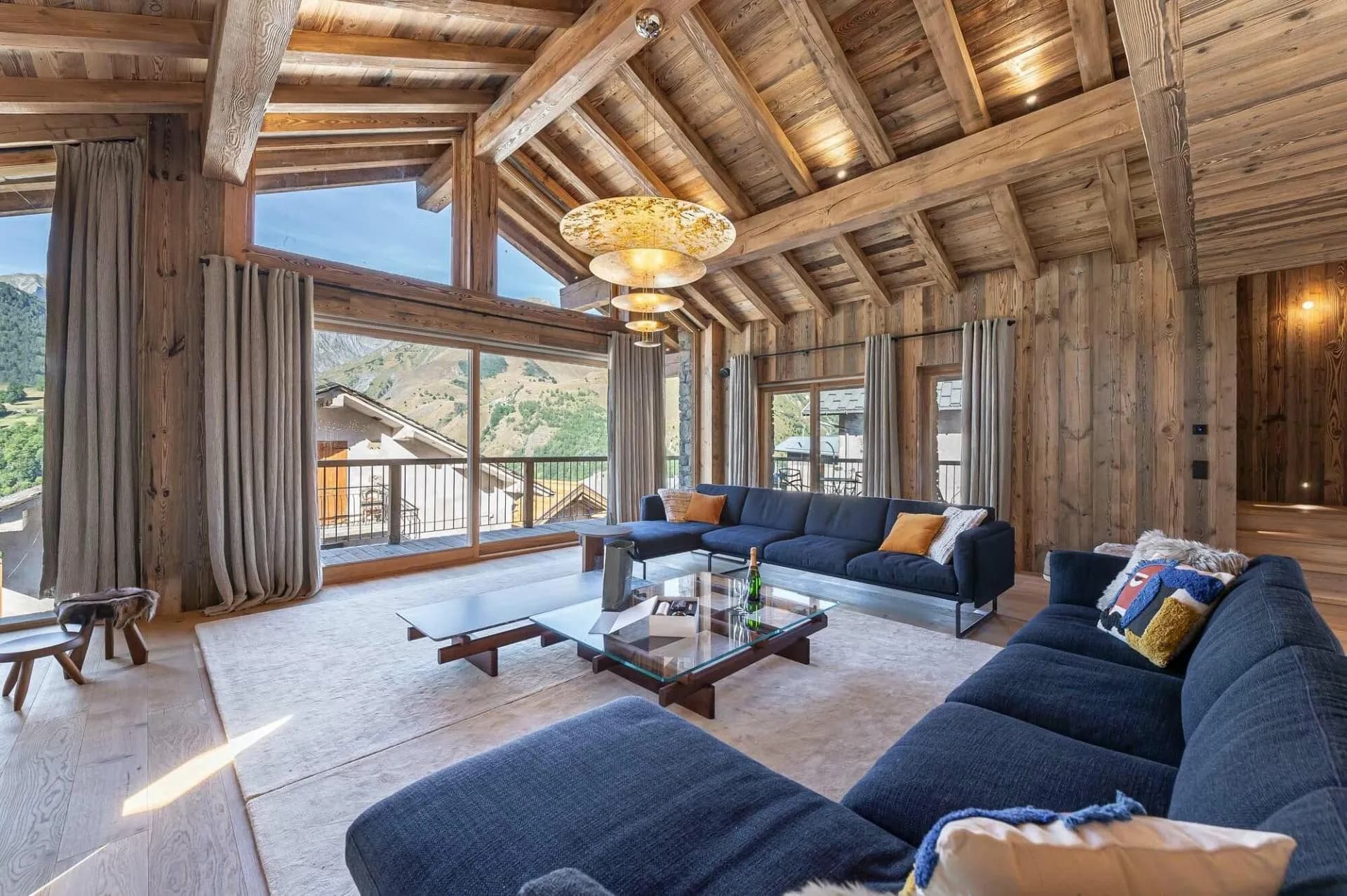 Living area beneath timber beams with a mountain-view balcony