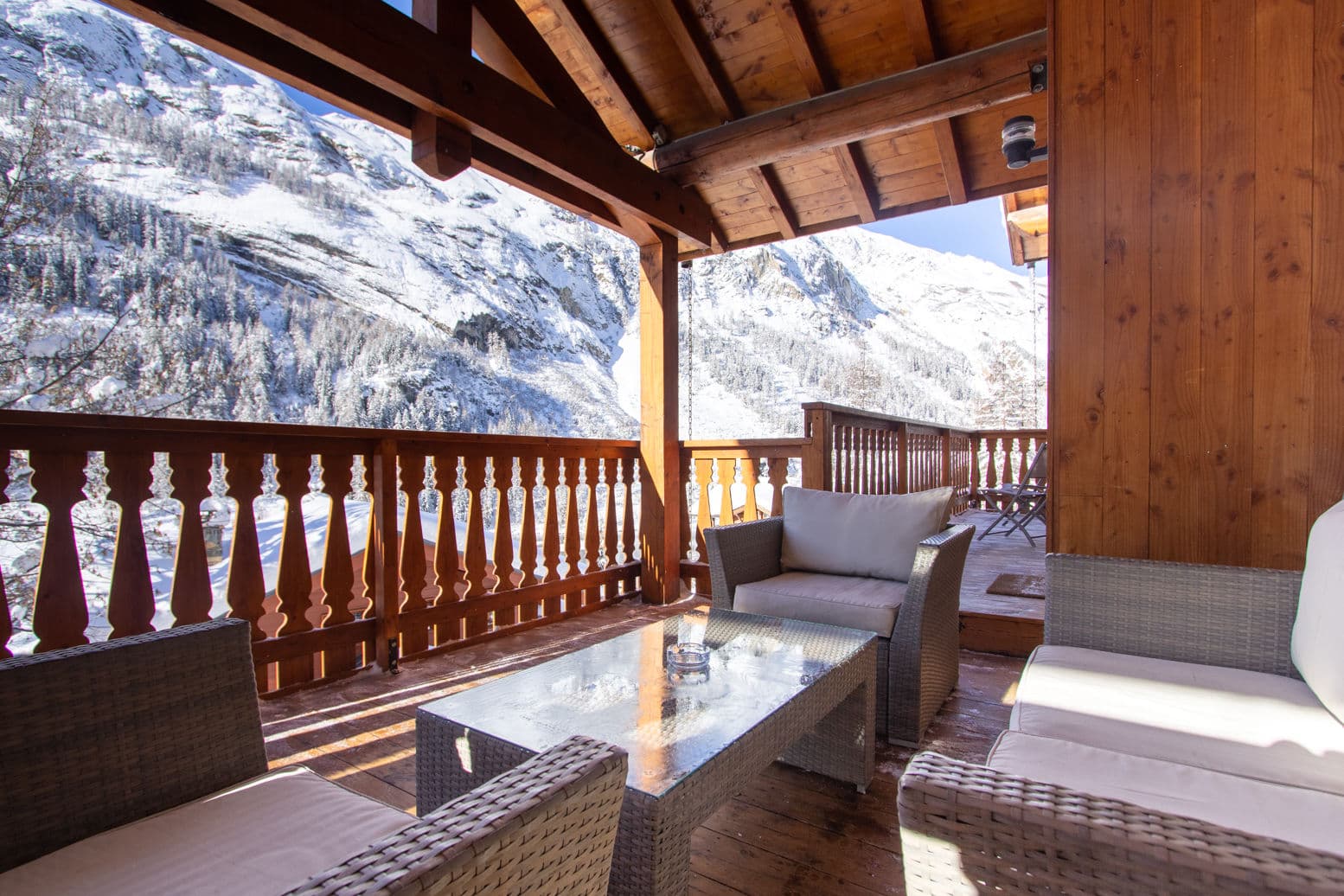 Covered balcony with snow-capped mountain views; rattan seating for 4