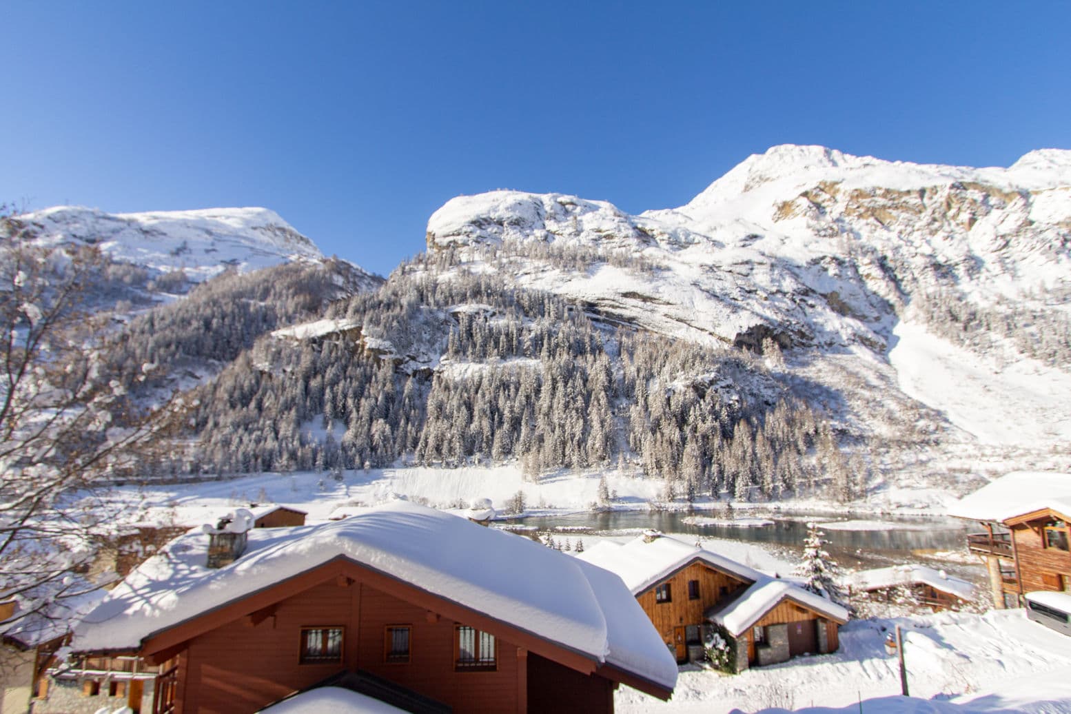 Lakefront cabins with snow-covered roofs; alpine peaks and forested slopes backdrop