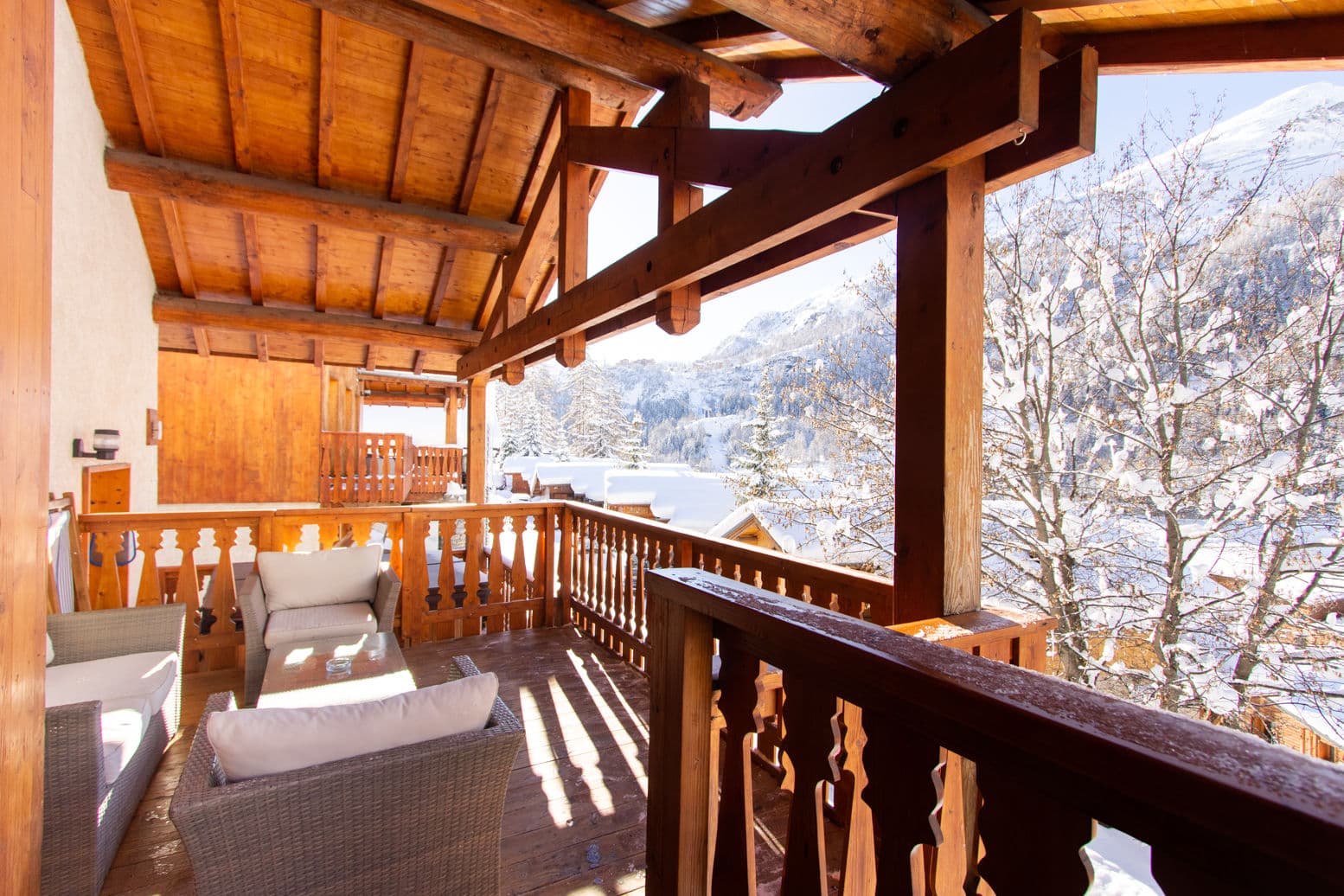 Covered deck with lounge seating and expansive lake and mountain views