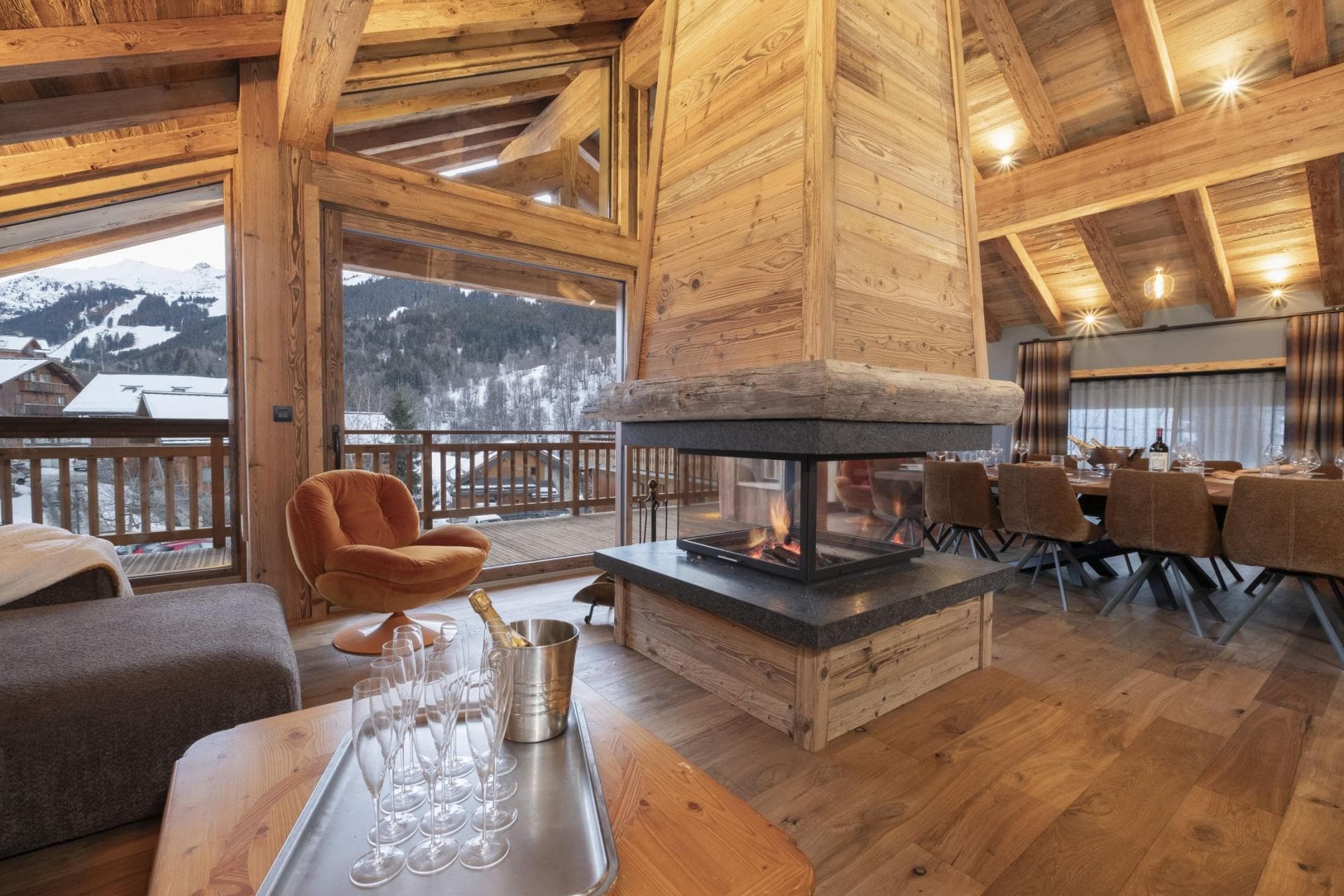 Central wood-burning fireplace sits between lounge and dining area with mountain views