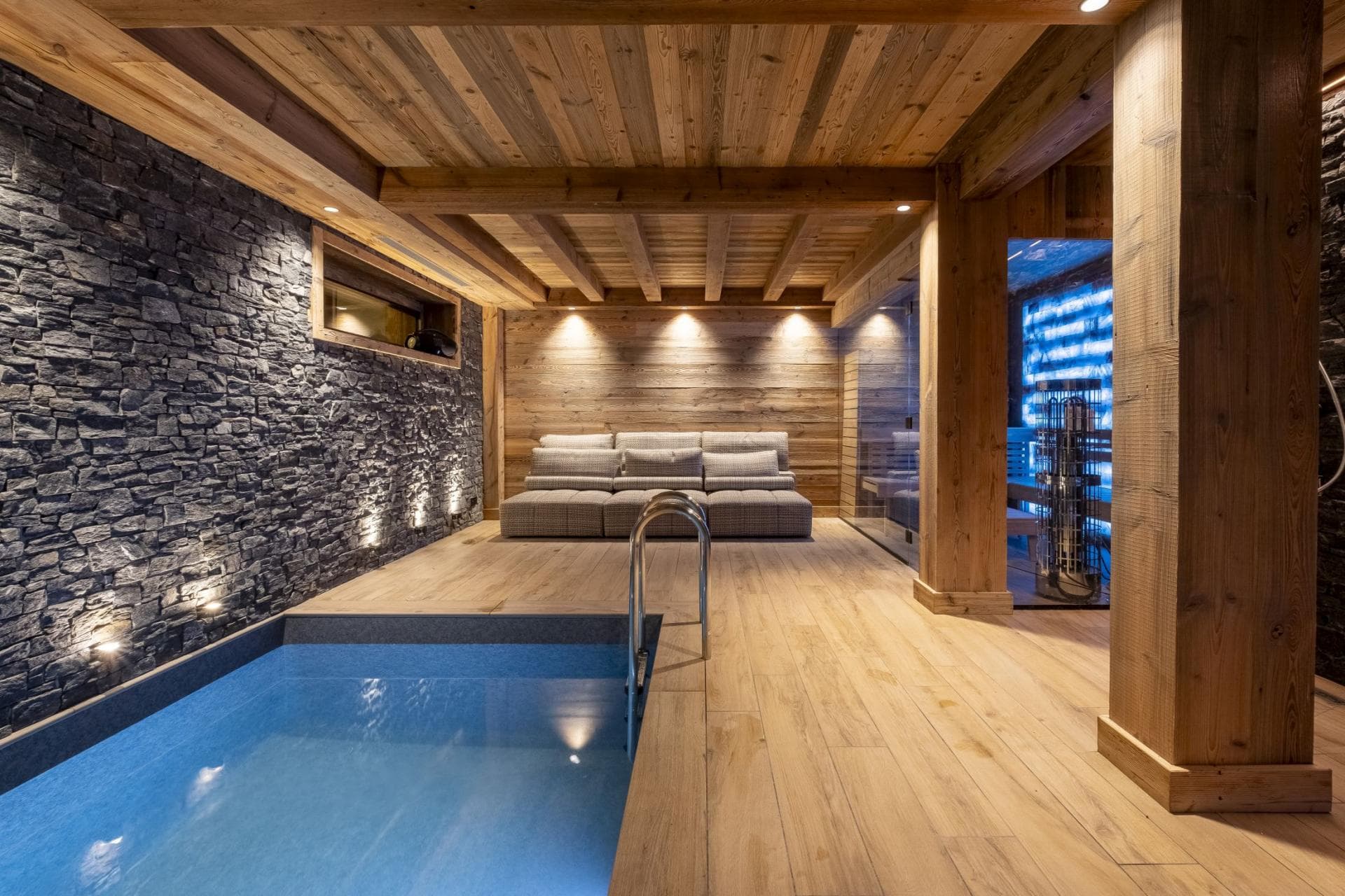 Indoor plunge pool and lounge area with adjacent glass sauna