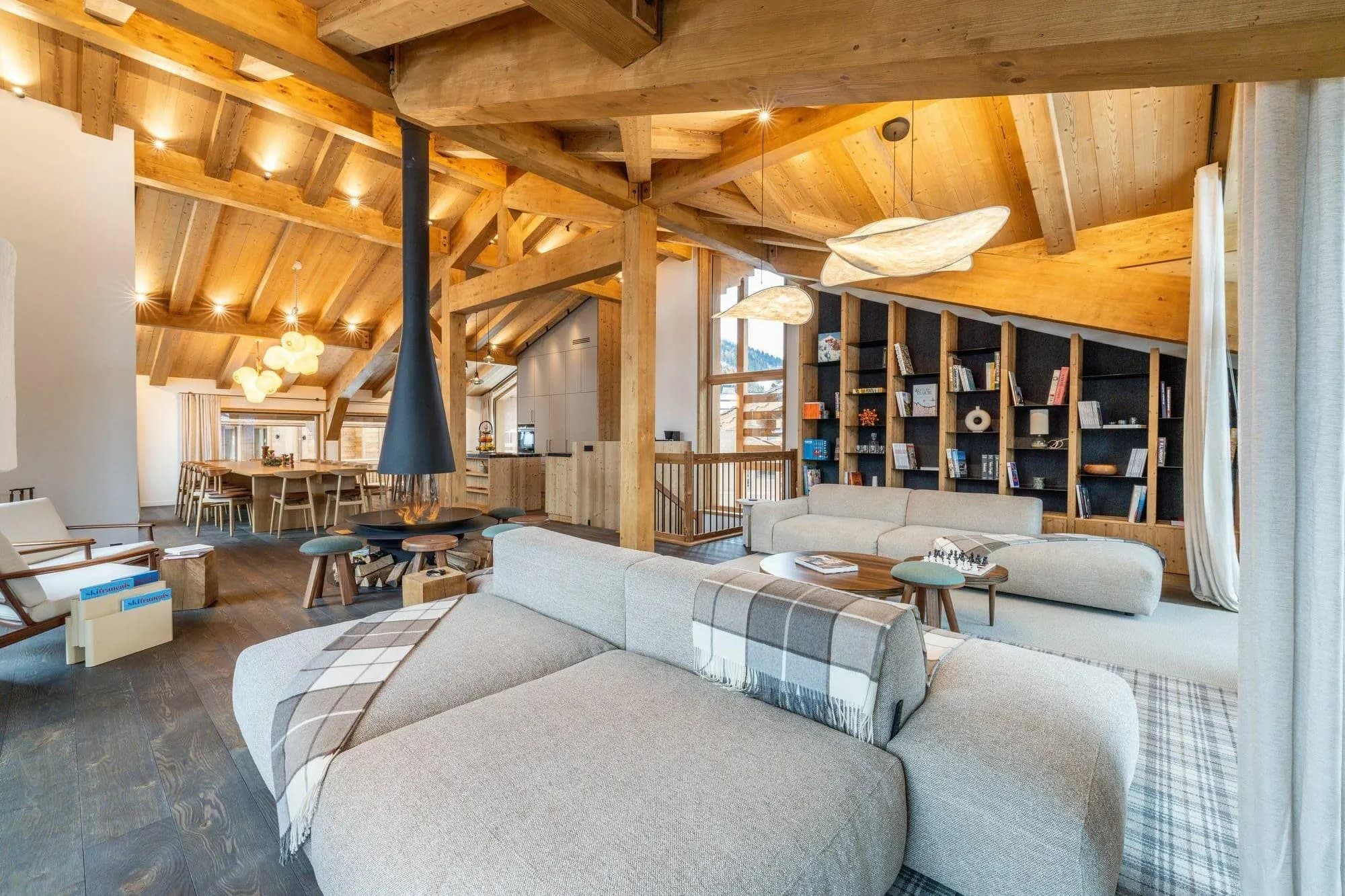 Open-plan living room with a central fireplace and vaulted timber ceiling