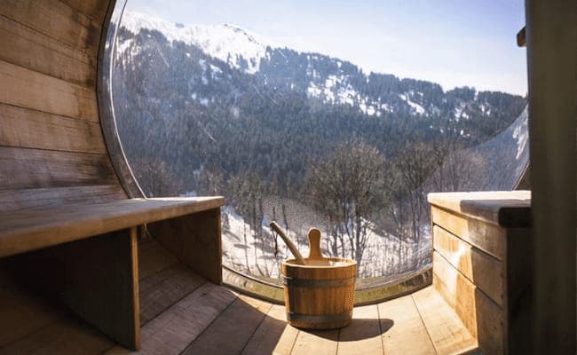 Barrel sauna with bubble window and snowy mountain views