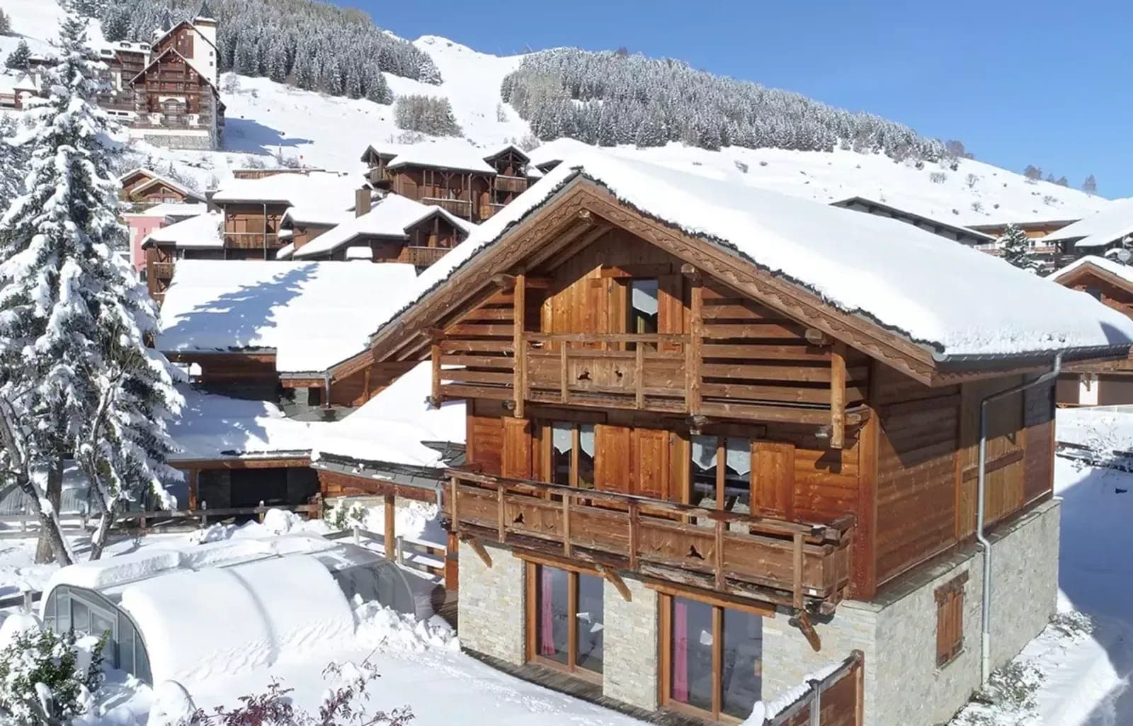 Ski-in chalet exterior with private pool and tiered wooden balconies