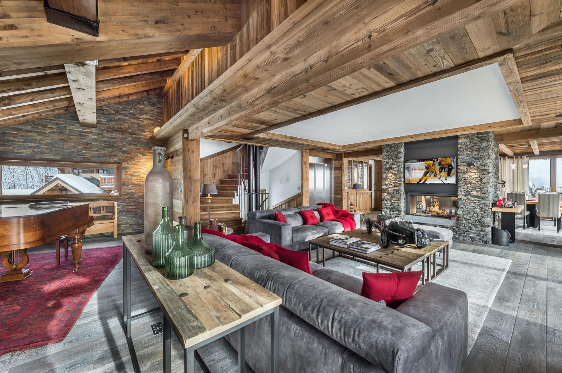 Living area with a grand piano, stone fireplace and internal elevator