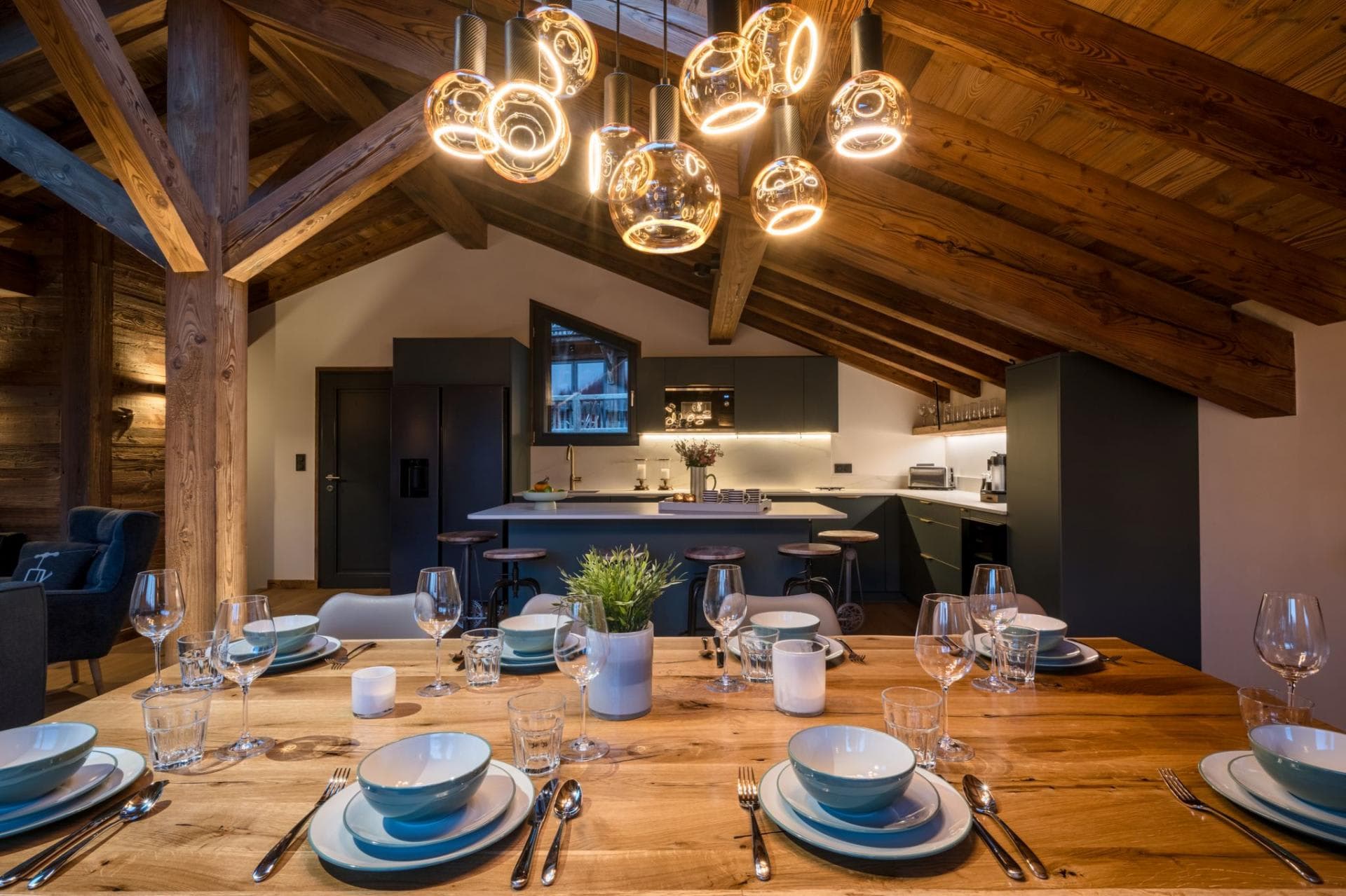 Dining area facing the open kitchen beneath exposed timber beams