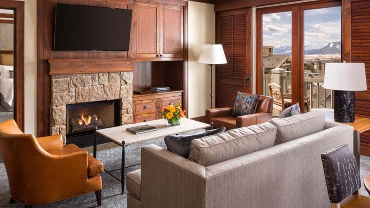 Living area with stone fireplace and private balcony access