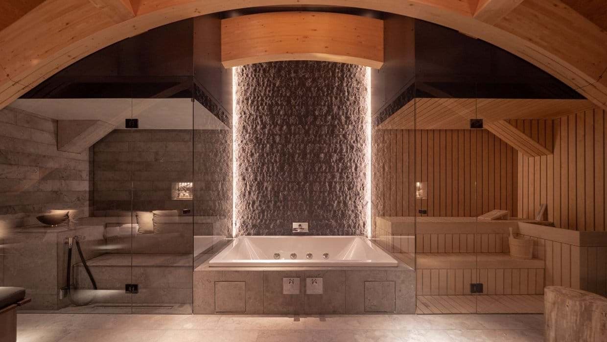 Wellness area with central soaking tub flanked by steam room and sauna
