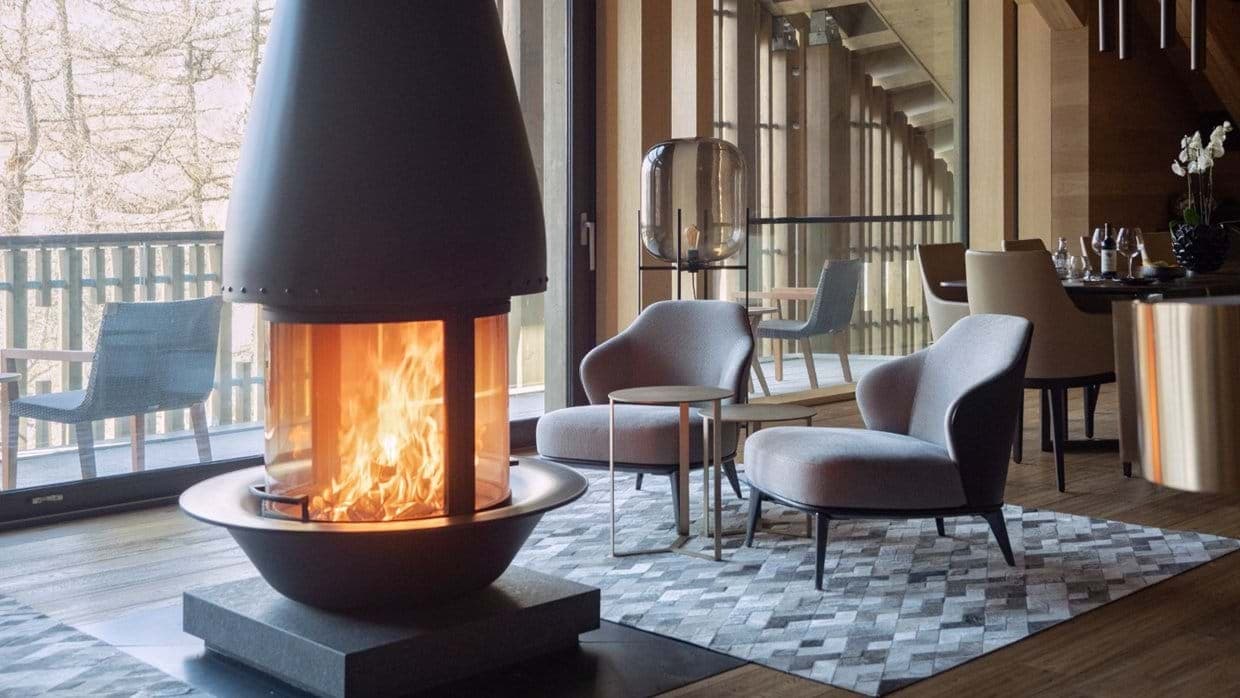 Central wood-burning fireplace with 360-degree glass and adjacent balcony access