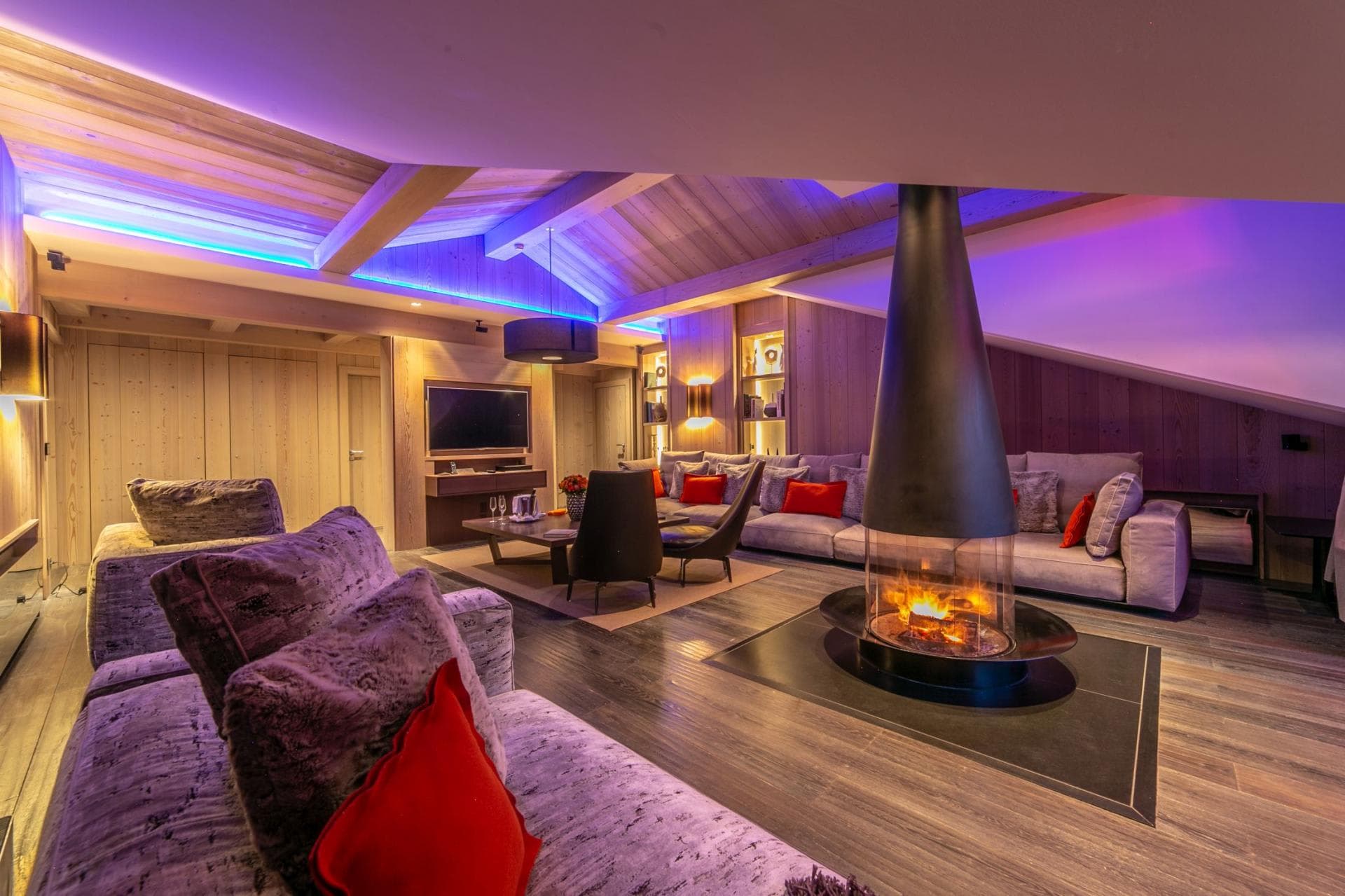 Living area with 360-degree glass fireplace and LED-backlit vaulted ceilings