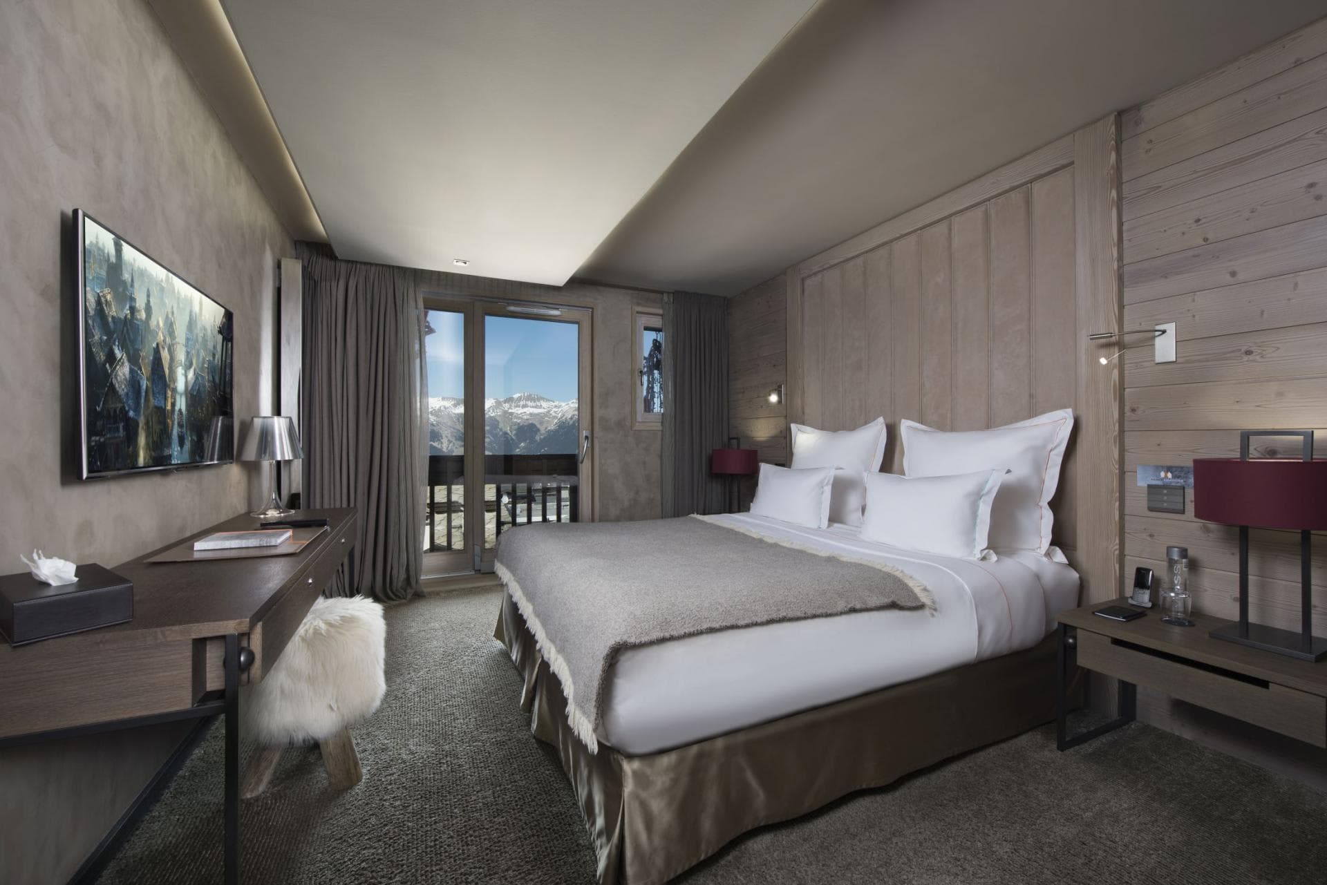 Primary bedroom with king bed, desk, and mountain-view balcony