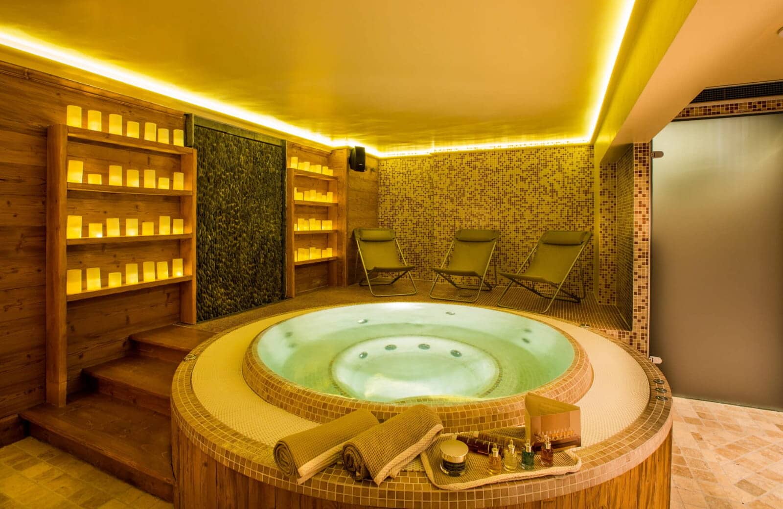 Indoor spa with circular hot tub, waterfall feature, and lounge seating