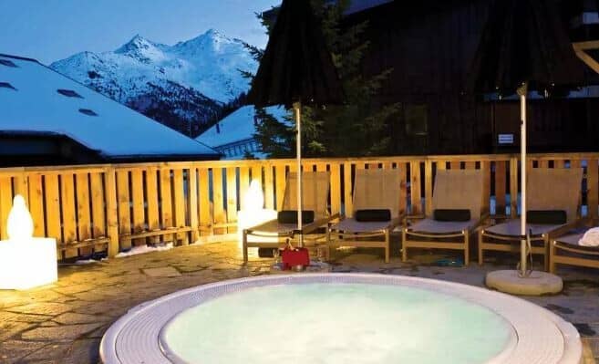 Outdoor hot tub and sun loungers with views of the Alps