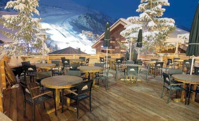 Outdoor terrace with patio seating and views of floodlit ski slopes