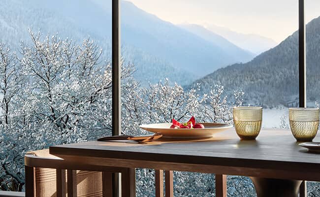 Dining table with floor-to-ceiling windows and alpine mountain views